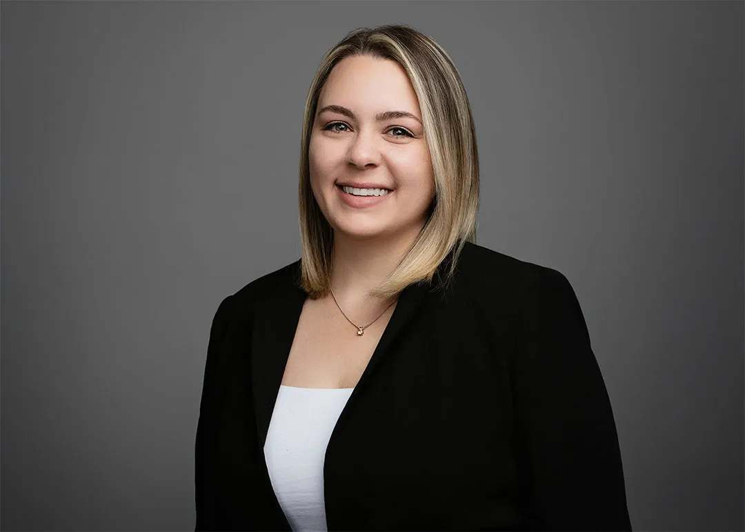 Smiling woman in black blazer and white shirt.