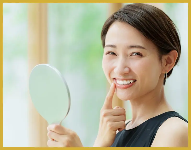 A woman holding her hand to her face and smiling.